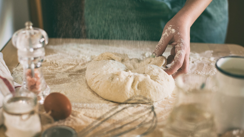 Someone rolling out dough for a pizza.