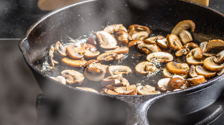 Sliced mushrooms cooking in a cast iron pan