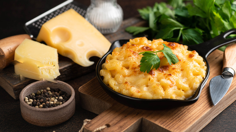 Cheesy mac and cheese in a cast iron dish surrounded by ingredients