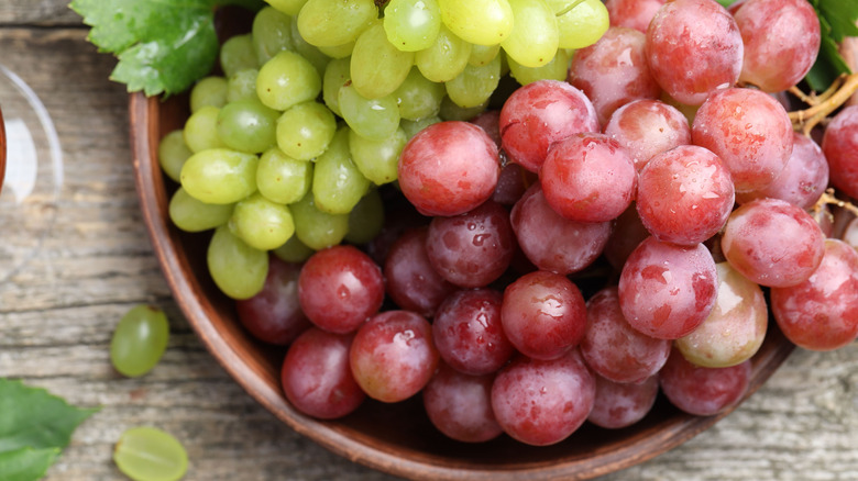 Green and red table grapes sitting in a bowl.