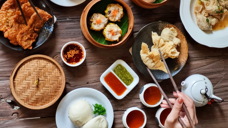 An assortment of Chinese delicacies and someone holding chopsticks