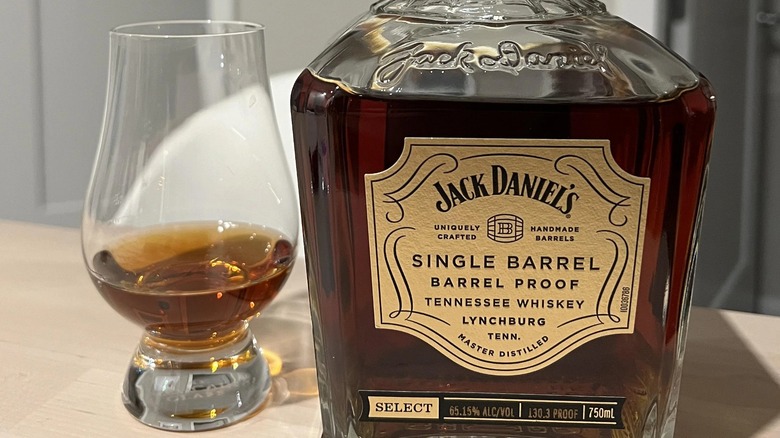 A glss of Jack Daniel's single barrel barrel proof Tennessee whiskey next to its bottle