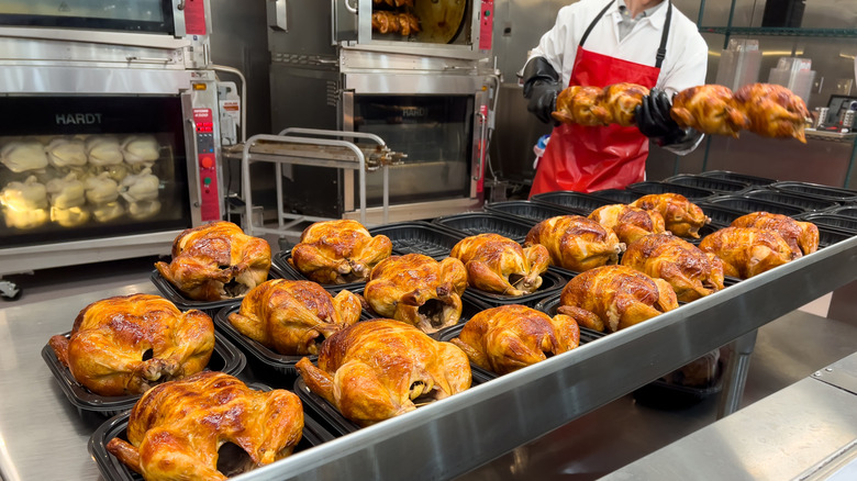 Man in red apron placing roasted chickens in containers