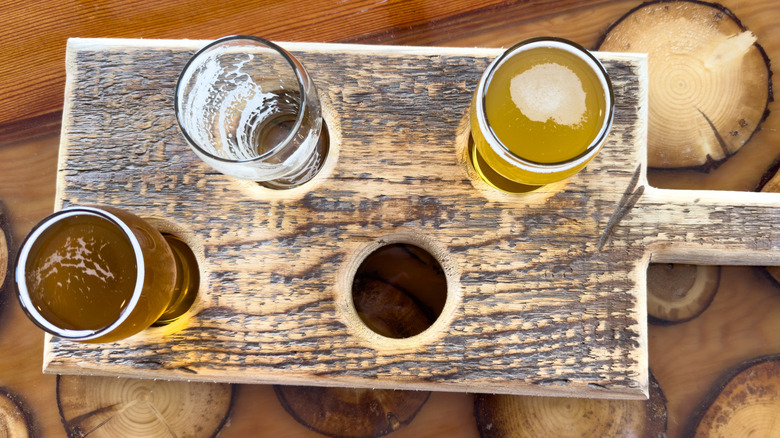 Four samples of various ales on a rectangular wooden serving board