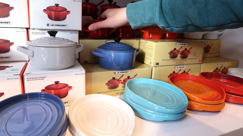 Someone looking through various sizes of colorful Dutch ovens