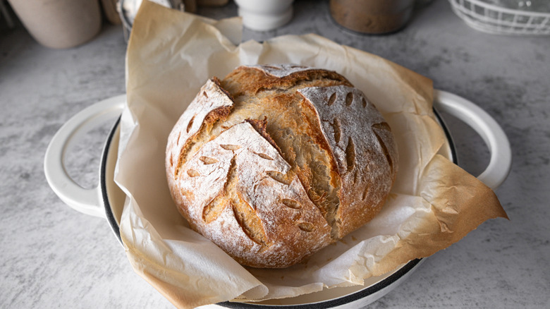 A loaf of sourdough bread in a white Dutch oven