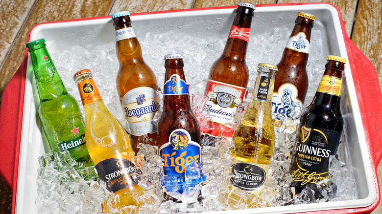 Several different brands of beer on ice in a red cooler