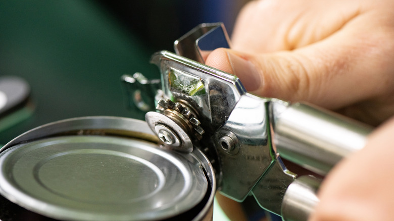 A person opening a can with can opener