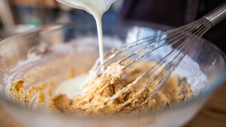 Milk being poured into a batter with a whisk