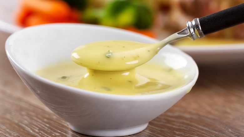 A white bowl of béarnaise sauce with a spoon