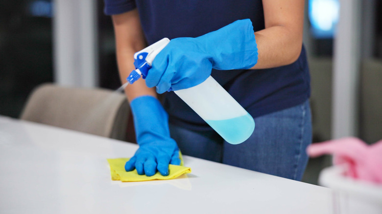 gloved hands sanitizing counter