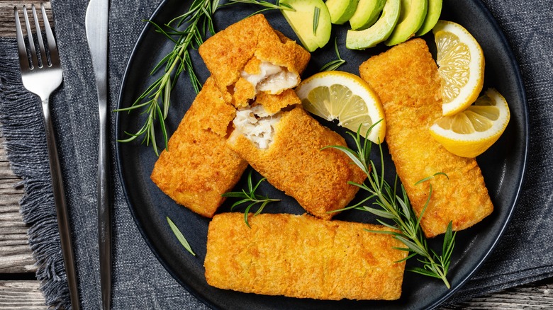 Alaska pollock fillets on a black plate with rosemary