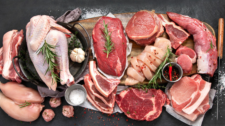 A selection of different raw meats on a wooden chopping block