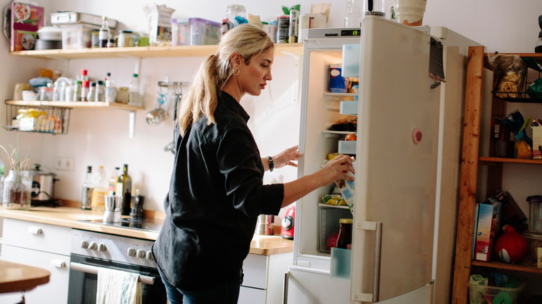 A woman standing in front of her open refrigerator