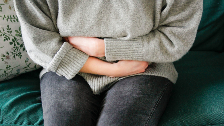 A woman sitting and clutching her stomach