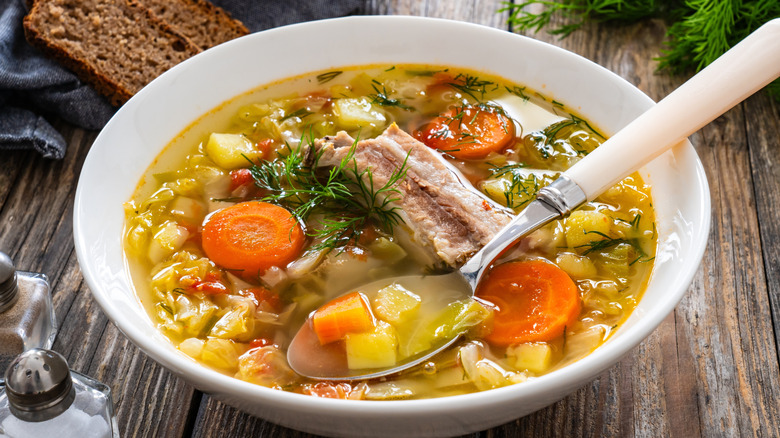 A bowl of soup with potato, cabbage, and pork