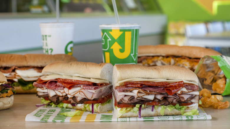 Subway sandwiches on a table with soft drinks