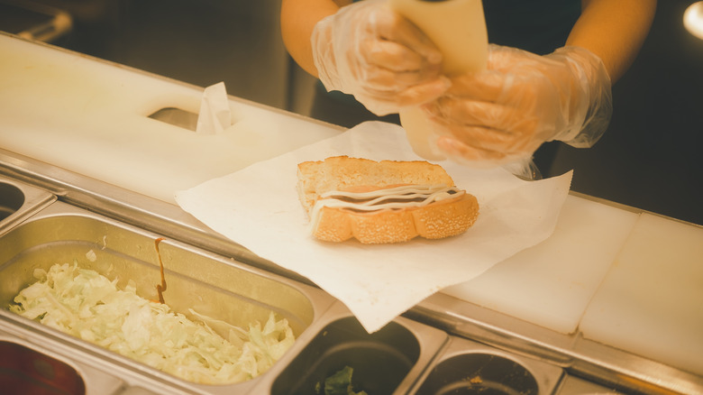 Hands of a Subway sandwich artist making a sub