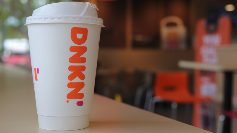 Hand holding a Dunkin Donuts iced coffee beverage.