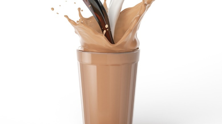 Coffee and milk are blended in a tall glass.