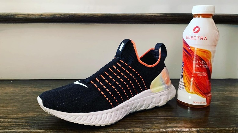 Electra orange drink next to a new Nike sneaker