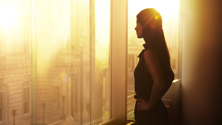 Businesswoman staring out window at sunset