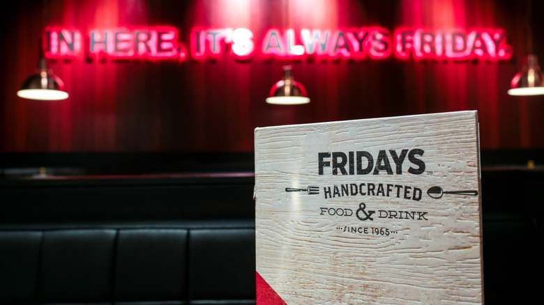 A TGI Fridays menu stands on a table. A sign reading "In here, it's always Friday" is seen in the background