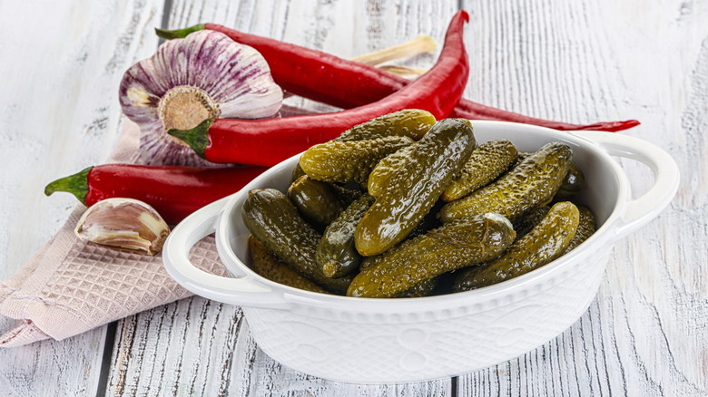 Cornichons in a white bowl with garlic and chili