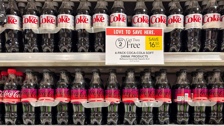 Shelves in a grocery store stacked with bottles of Coke Zero and Diet Coke.