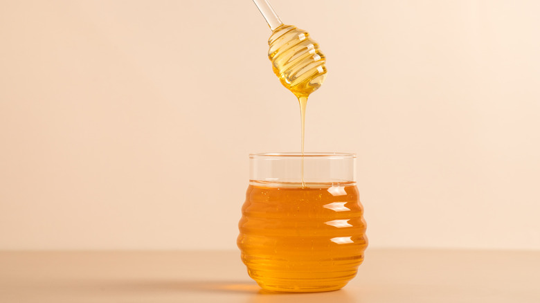 Liquid honey being poured from honey dipper