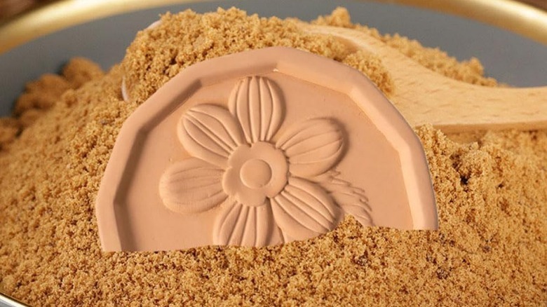 floral-patterned terracotta disc in a bowl of brown sugar