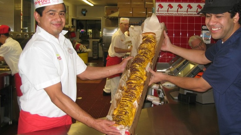 An In-N-Out worker and a customer posing with the 100x100 burger inside an In-N-Out.