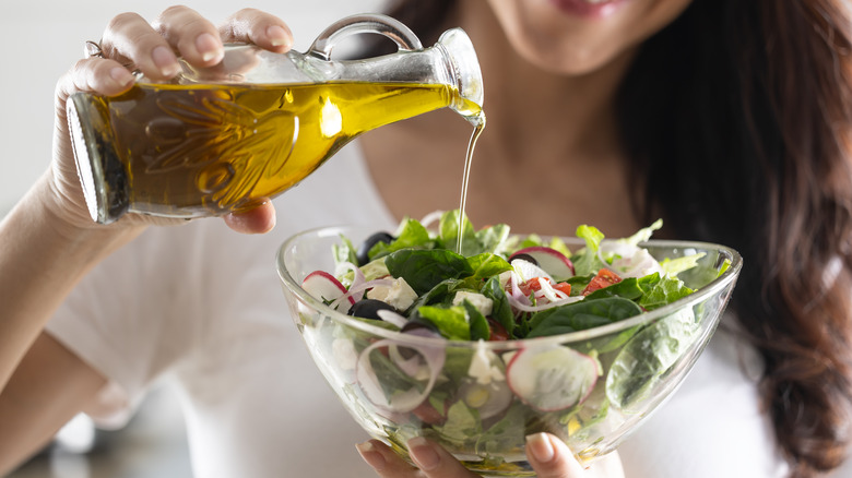 Woman pouring olive oil on her salad