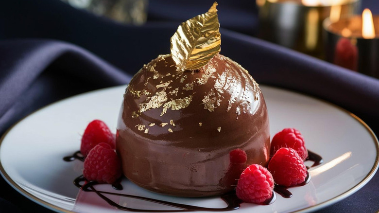 Chocolate mousse with a thin layer of ganache on top, decorated with gold leaf and raspberries.