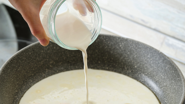 A person pouring cream into a pan