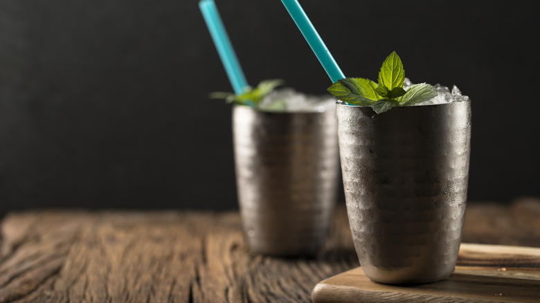 Two Moscow mule cocktails in metal cups with crushed ice and mint garnishes