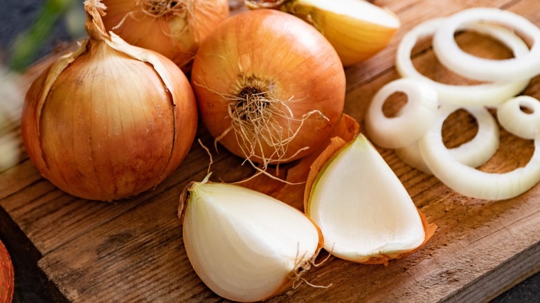 A number of yellow onions, some halved and some sliced into rings.