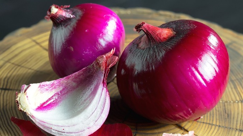 Red onions on a place setting that resembles a tree stump.