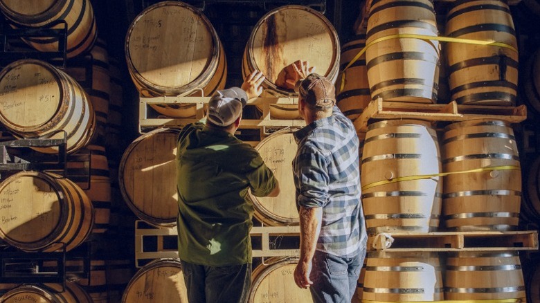 Distillers review barrels of aging bourbon in the storehouse.