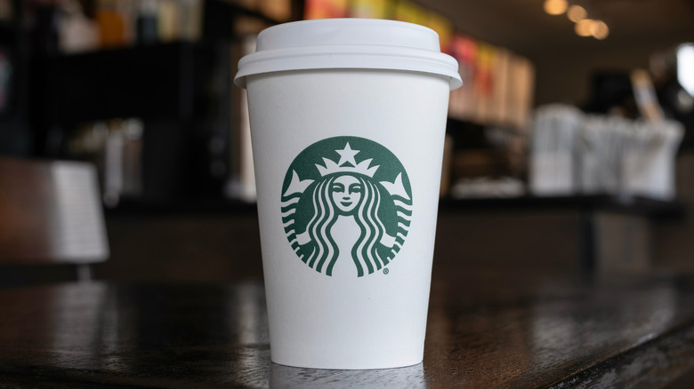 A white Starbucks takeaway coffee cup with the famous green logo