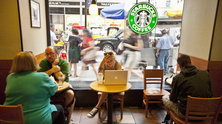 Inside a Starbucks store with people drinking coffee and using their computers at the tables