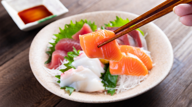 A dish full of different kinds of Japanese sashimi, including salmon.