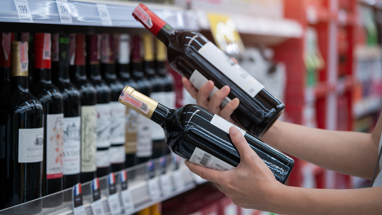 A person holding two bottles of wine at the grocery store