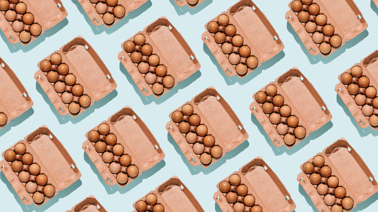 Overhead view of several open egg cartons. Brown eggs inside. Pale blue background