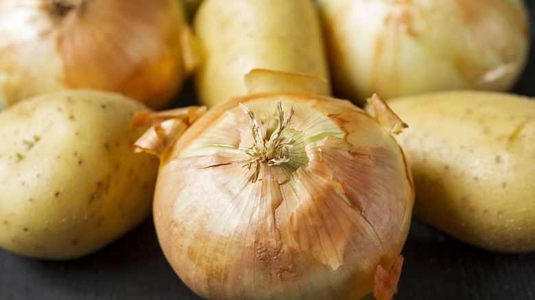 Potatoes and onions lying next to one another.