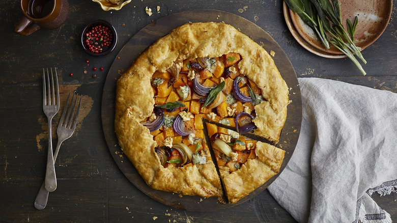 Galette on wooden board with squash and walnuts