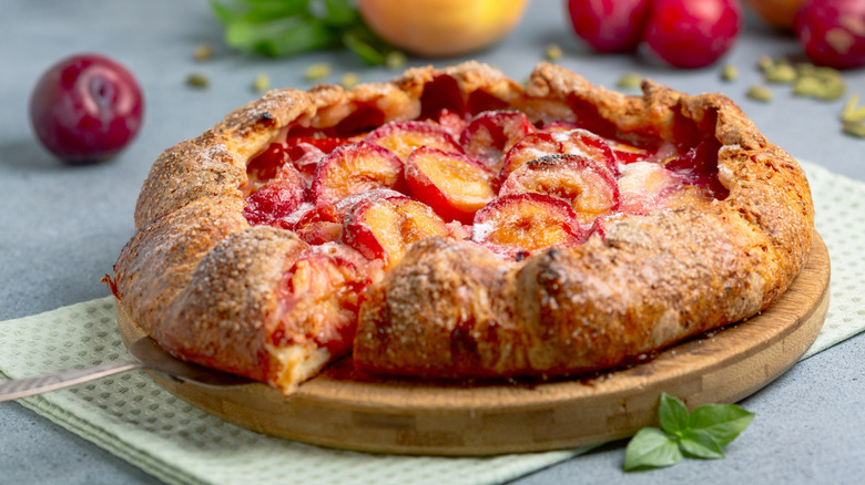 Plum galette on wooden board and dish towel