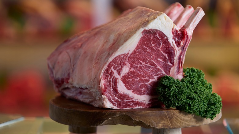 raw prime rib with parsley on wooden stand