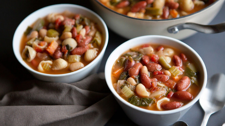 bowls of bean and pasta soup next to pot of the same