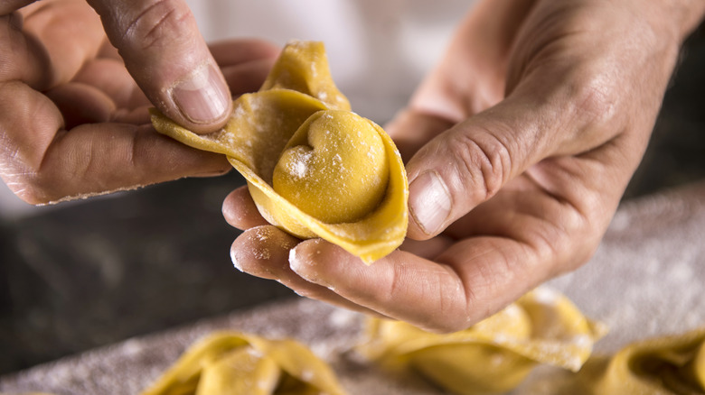 A person folding fresh tortellini pasta